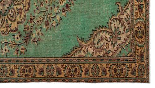 Load image 1 in gallery view. Distressed emerald green rug with a tan floral border and intricate brown and beige medallion pattern.