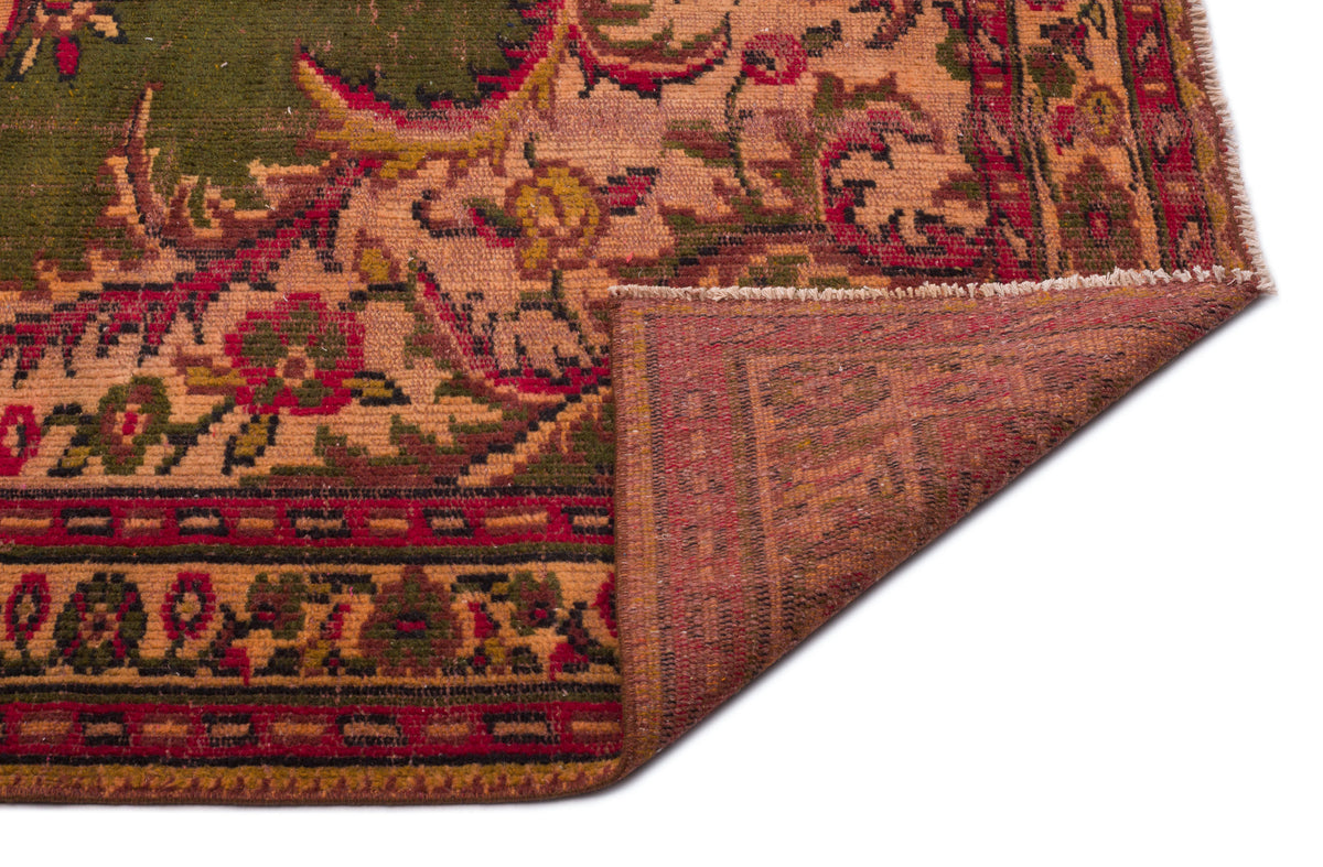 Olive green and rust red traditional rug with a floral medallion pattern, shown with a corner folded over.