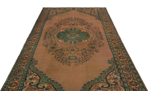 Load image 1 in gallery view. Tan traditional rug with a central green and brown floral medallion and a decorative border on a white background.