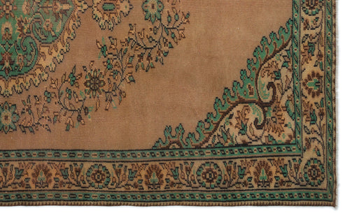 Load image 1 in gallery view. Tan vintage rug with a green and brown floral medallion pattern and a decorative geometric border.