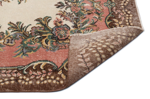 Load image 1 in gallery view. Cream, pink, and brown floral medallion rug with a folded corner showing the woven backing on a white background.
