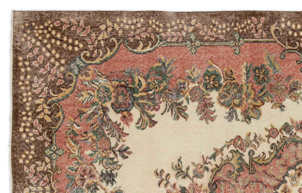 Vintage-style rug corner with a cream center, terracotta border, and intricate floral patterns in green and brown.