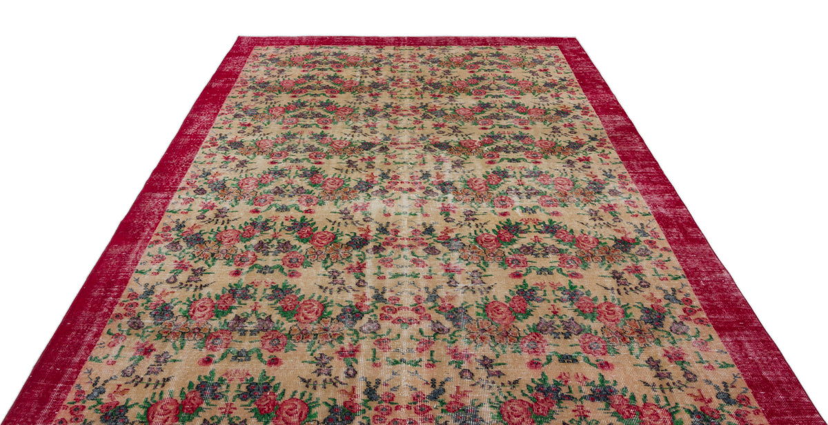 Beige rug with a distressed floral pattern in red, green, and blue, featuring a wide red border.