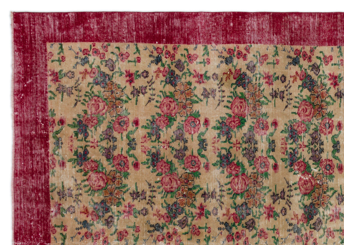 Distressed beige rug with a deep red border and a repeating floral pattern in red, green, and dark blue.