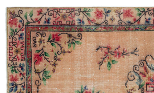 Load image 1 in gallery view. Peach-toned vintage rug with a floral vine border, geometric accents, and red, green, and blue botanical motifs.