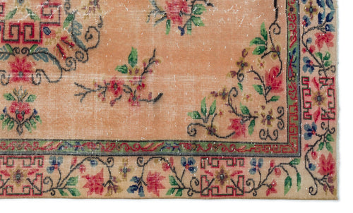 Load image 1 in gallery view. Peach-toned vintage rug with a distressed floral pattern, green border, and red geometric accents.