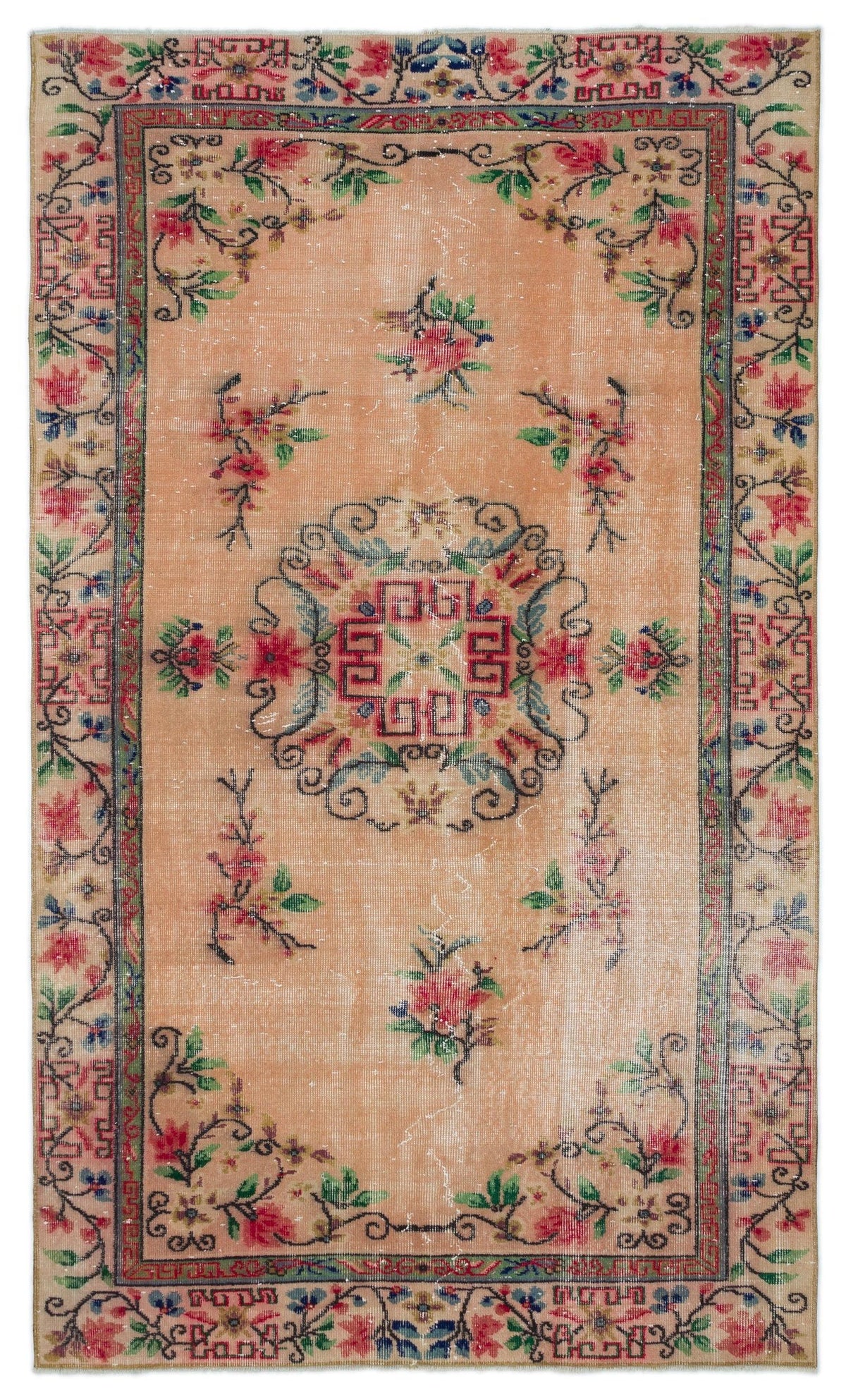 Peach-toned vintage rug with a central geometric medallion, floral motifs, and a decorative border in red, blue, and green.