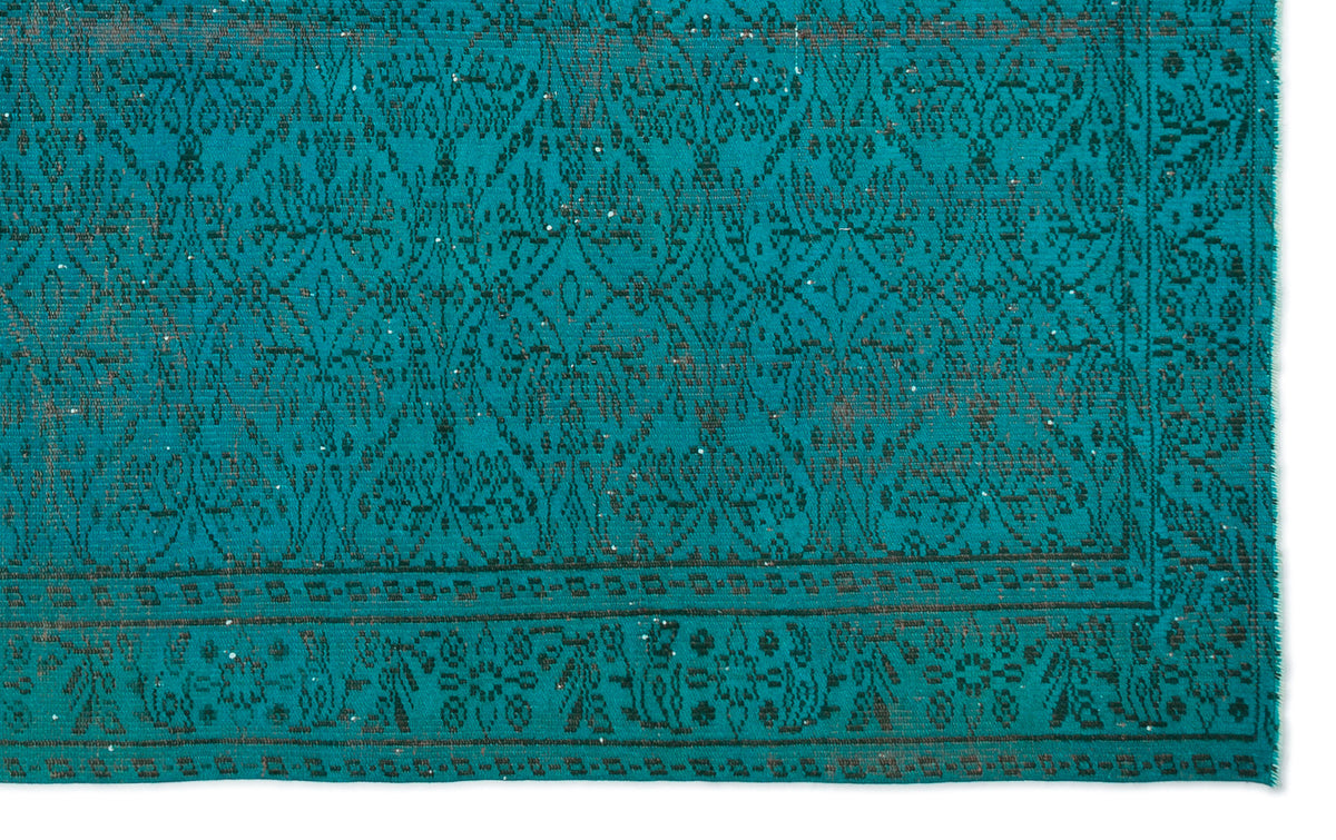 Teal rug with a dark charcoal distressed floral medallion pattern and a geometric border.
