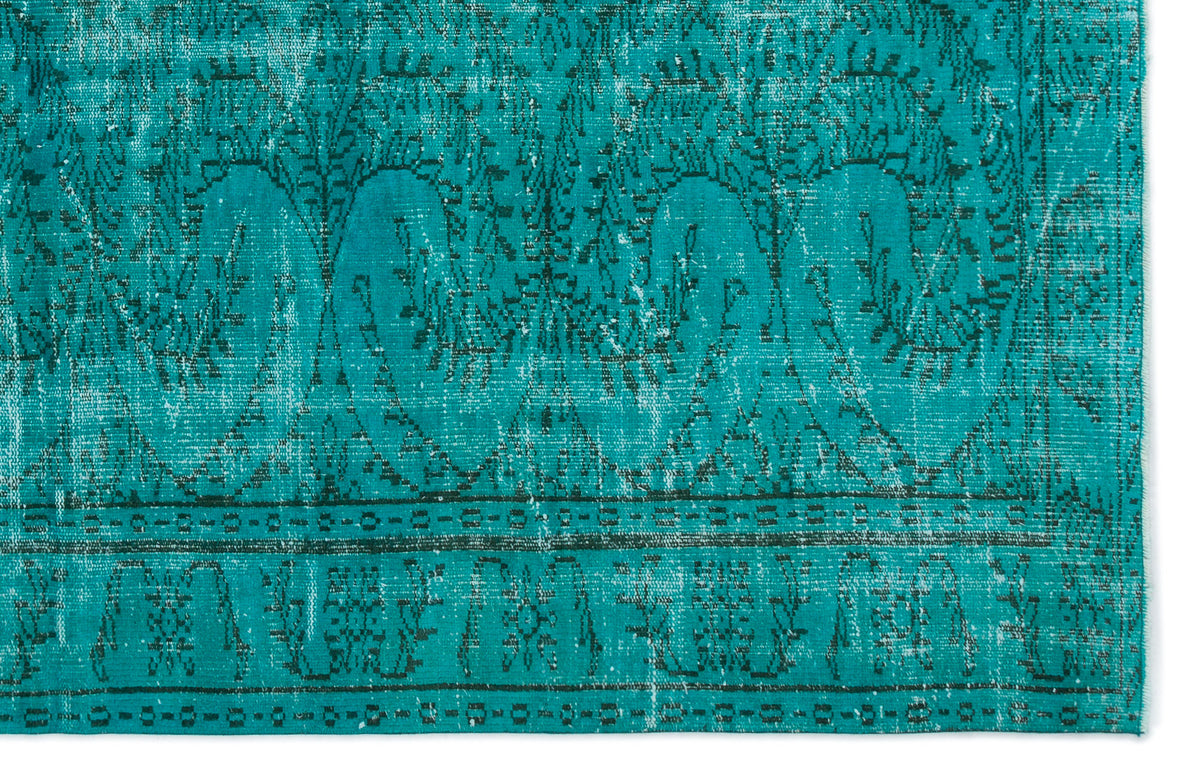 Teal rug with a distressed, dark green traditional floral pattern and geometric border on a white background.