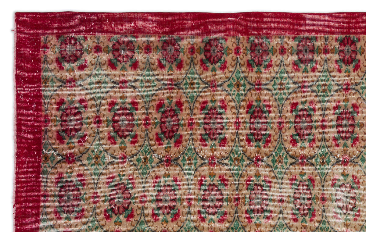 Distressed tan rug with a red border and a repeating pattern of red floral medallions and green geometric diamonds.