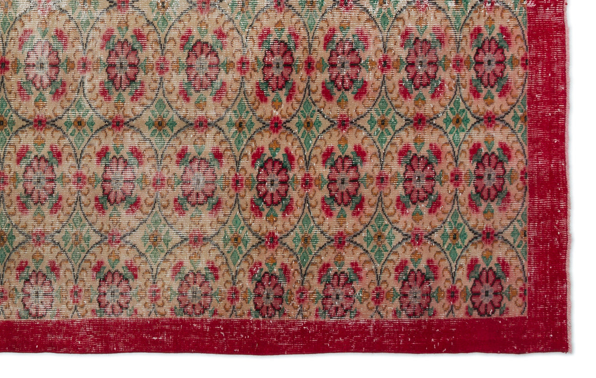 Beige rug with a repeating floral medallion pattern in red and green, featuring a solid red border.