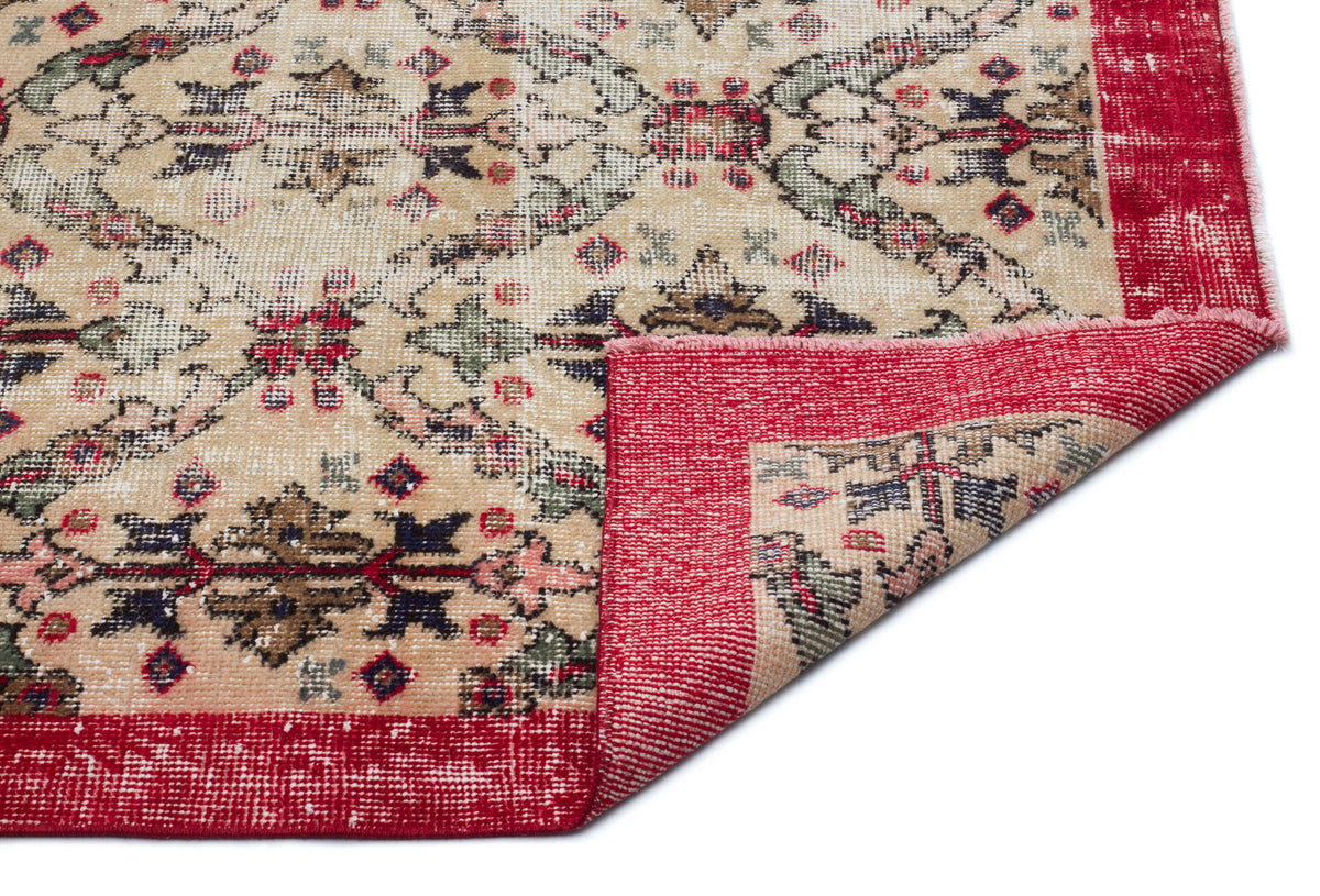 Beige vintage-style rug with a red border and multi-colored floral medallion pattern, shown with a folded corner.