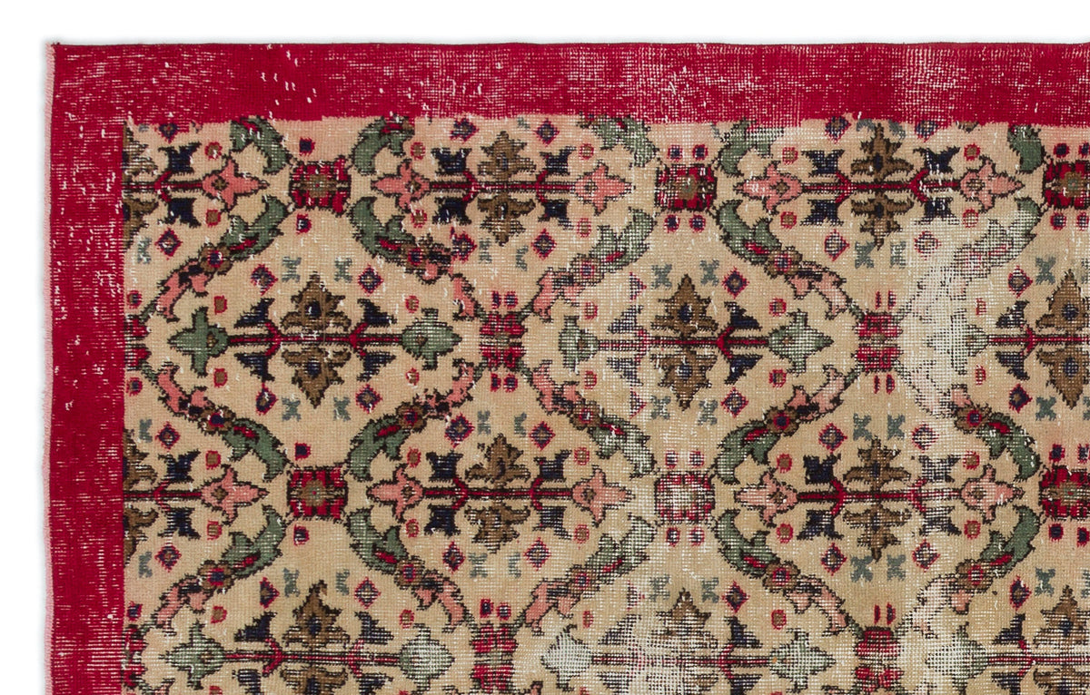Beige vintage-style rug with a red border and a repeating floral medallion pattern in red, green, and dark brown.