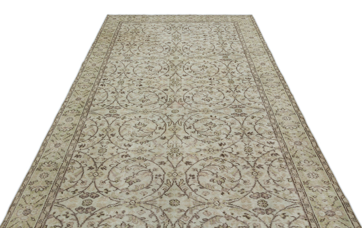 Beige and brown vintage-style rug with a repeating floral medallion pattern and a decorative border.