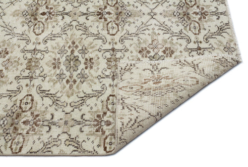 Load image 1 in gallery view. Beige and brown traditional floral medallion rug with a distressed finish, shown with a corner folded over.