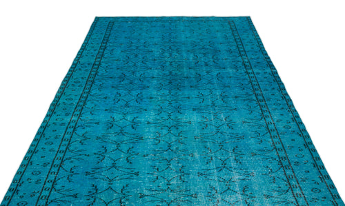 Load image 1 in gallery view. Bright turquoise rug with a distressed black geometric floral pattern and a bordered edge on a white background.