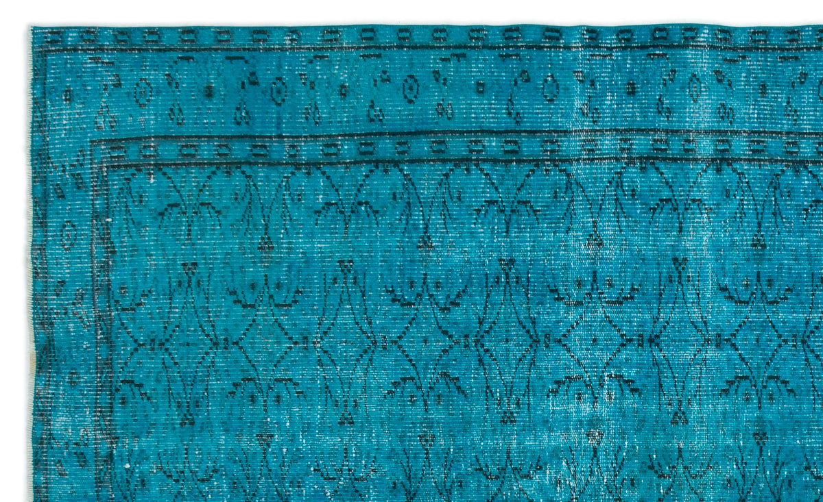 Teal rug with a distressed black geometric floral pattern and a bordered edge on a white background.