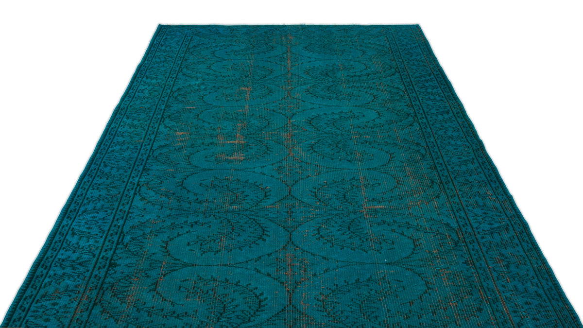 Teal distressed rug with a repeating dark floral medallion pattern and a bordered edge on a white background.