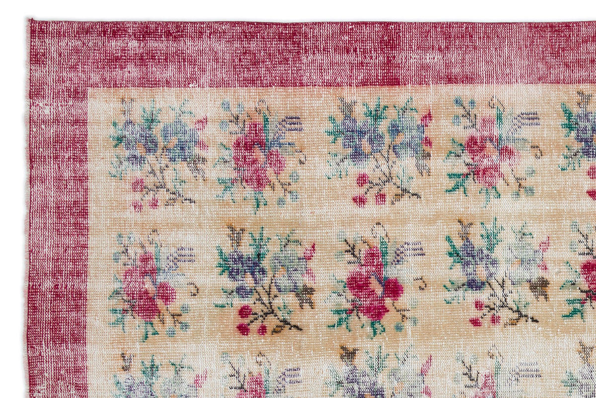 Beige rug with a distressed magenta border and a repeating grid of small, multi-colored floral bouquets.