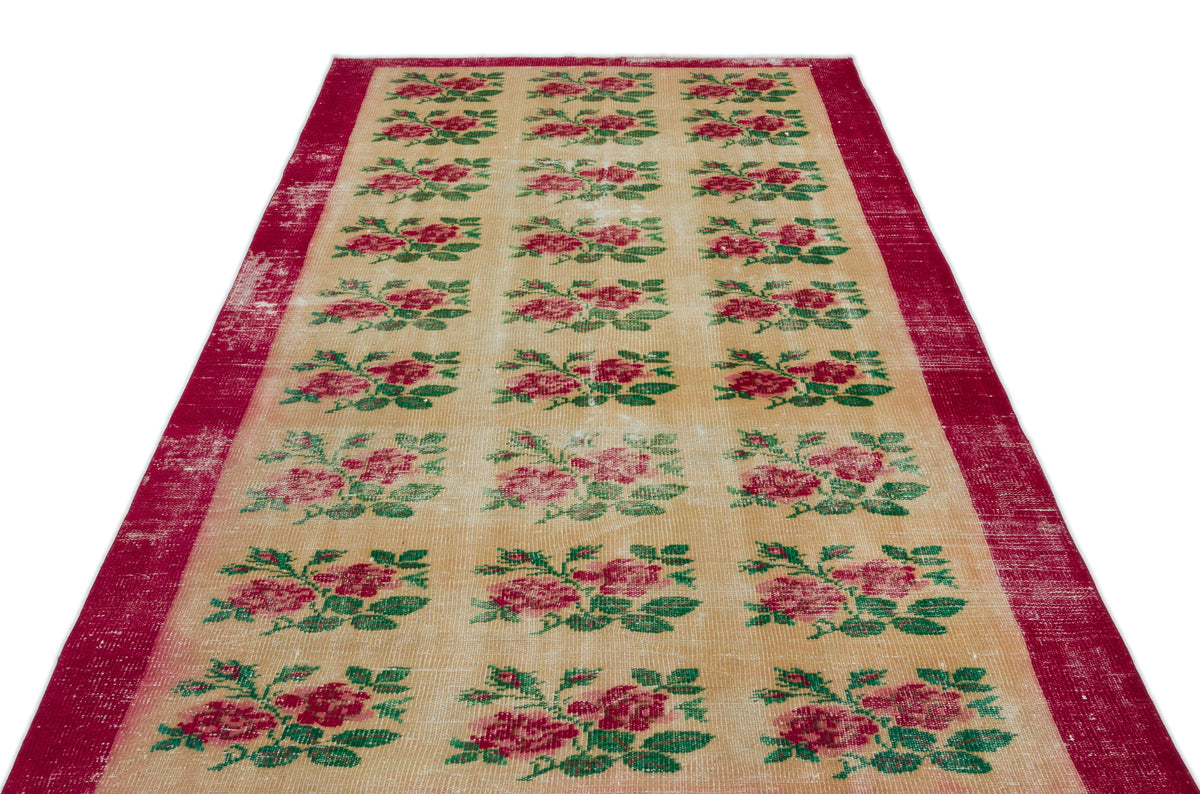 Beige runner rug with a repeating red rose and green leaf pattern and a distressed red border.