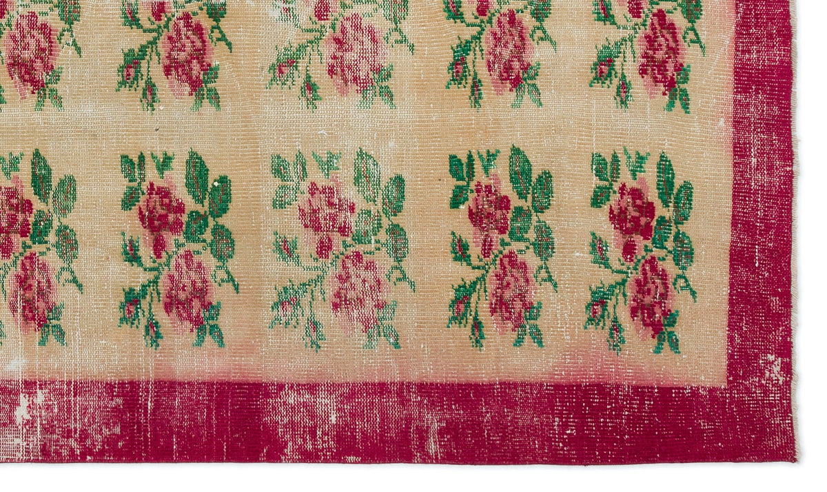 Beige rug with a repeating floral pattern of pink roses and green leaves, featuring a distressed deep pink border.
