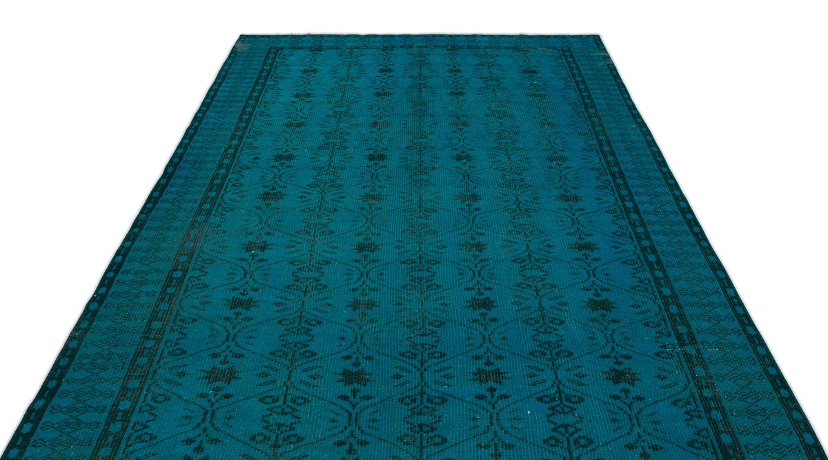 Teal rug with a dark geometric lattice and floral motif on a white background.