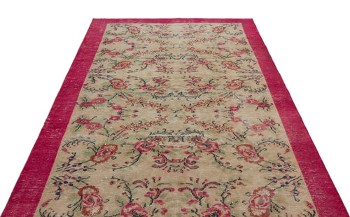 Load image 1 in gallery view. Beige vintage-style rug with a distressed floral pattern and a wide, solid magenta border.
