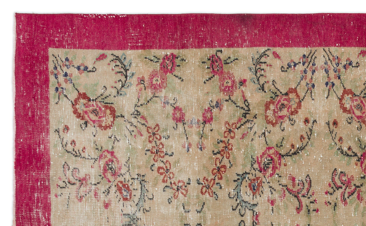 Distressed beige rug with a wide magenta border and a floral vine pattern in red, green, and black.