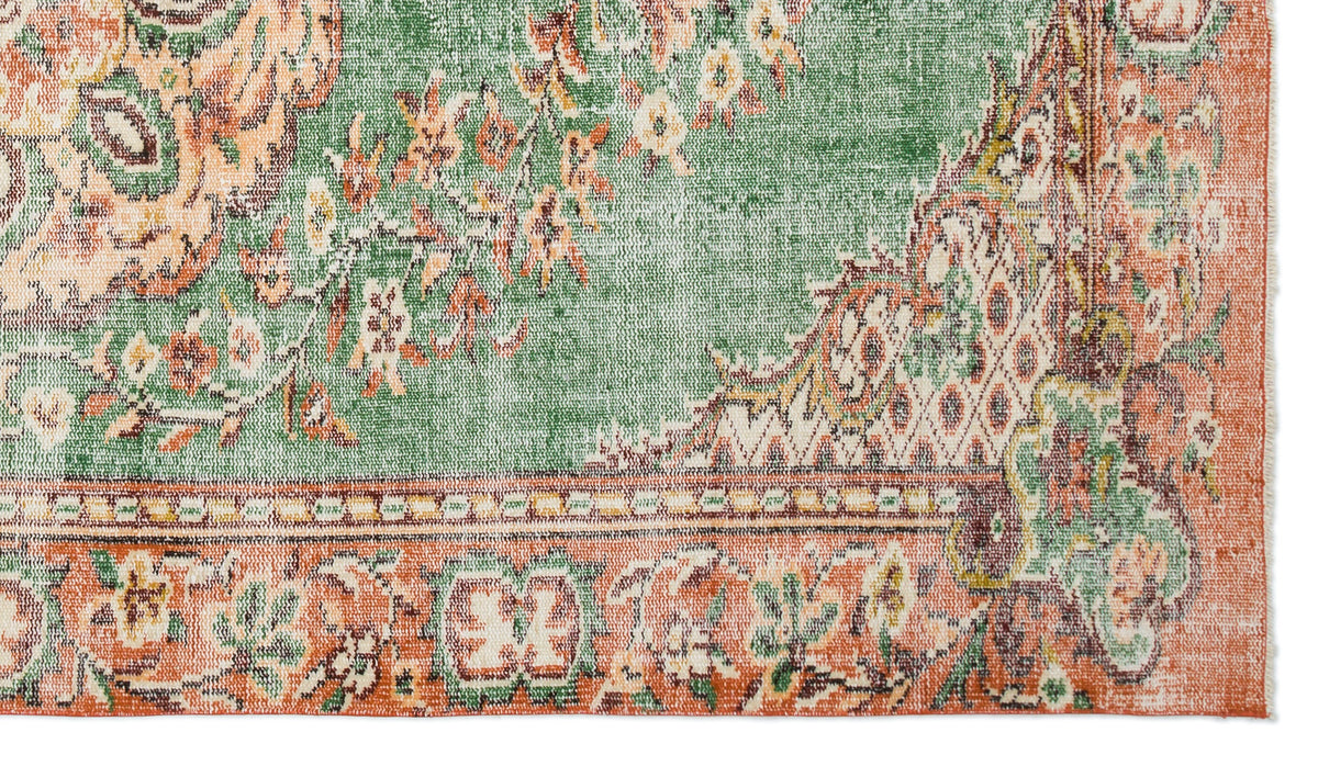 Distressed green and terracotta rug with a traditional floral medallion pattern and a decorative border.