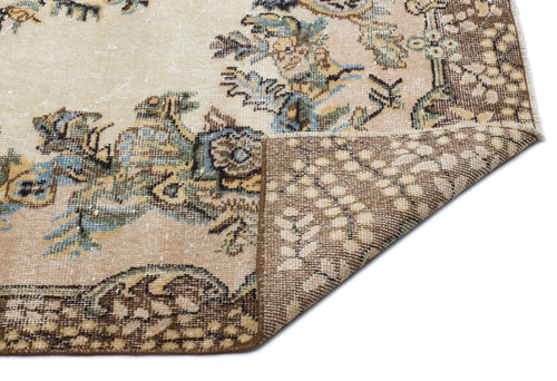 Load image 1 in gallery view. Beige and brown vintage-style rug with a floral medallion pattern and a folded corner showing the woven backing.