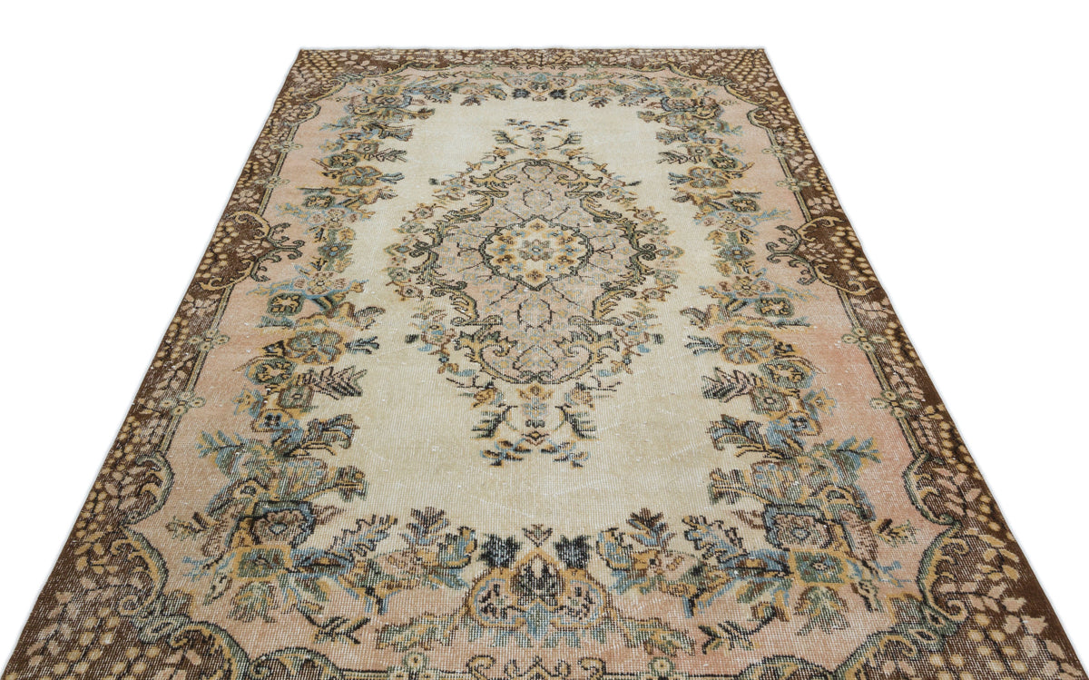 Beige and peach vintage-style rug with a central floral medallion and dark brown ornate border.