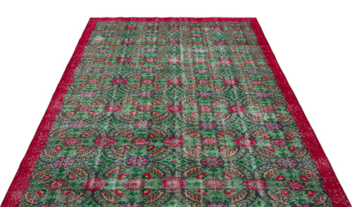 Load image 1 in gallery view. Distressed green rug with a repeating red and blue floral medallion pattern and a solid red border.