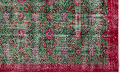 Load image 1 in gallery view. Distressed green rug with a repeating floral medallion pattern in red and tan, featuring a solid red border.