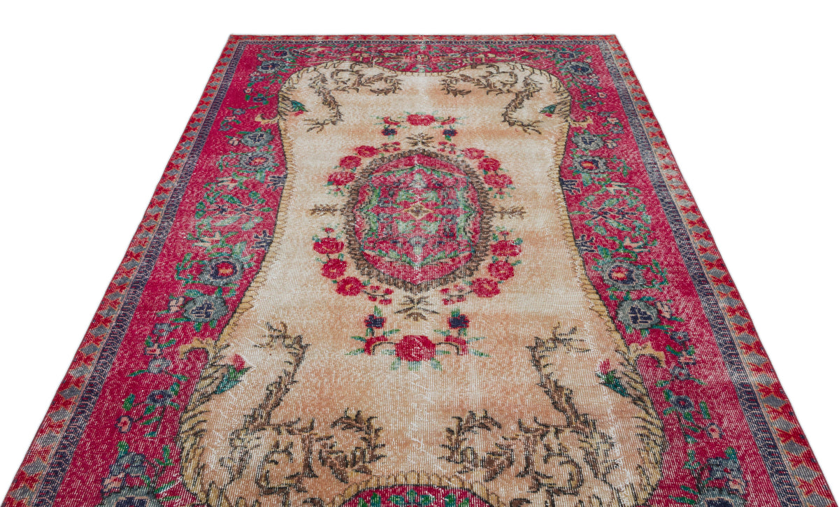 Distressed vintage-style rug with a central floral medallion, cream field, and wide magenta border on a white background.