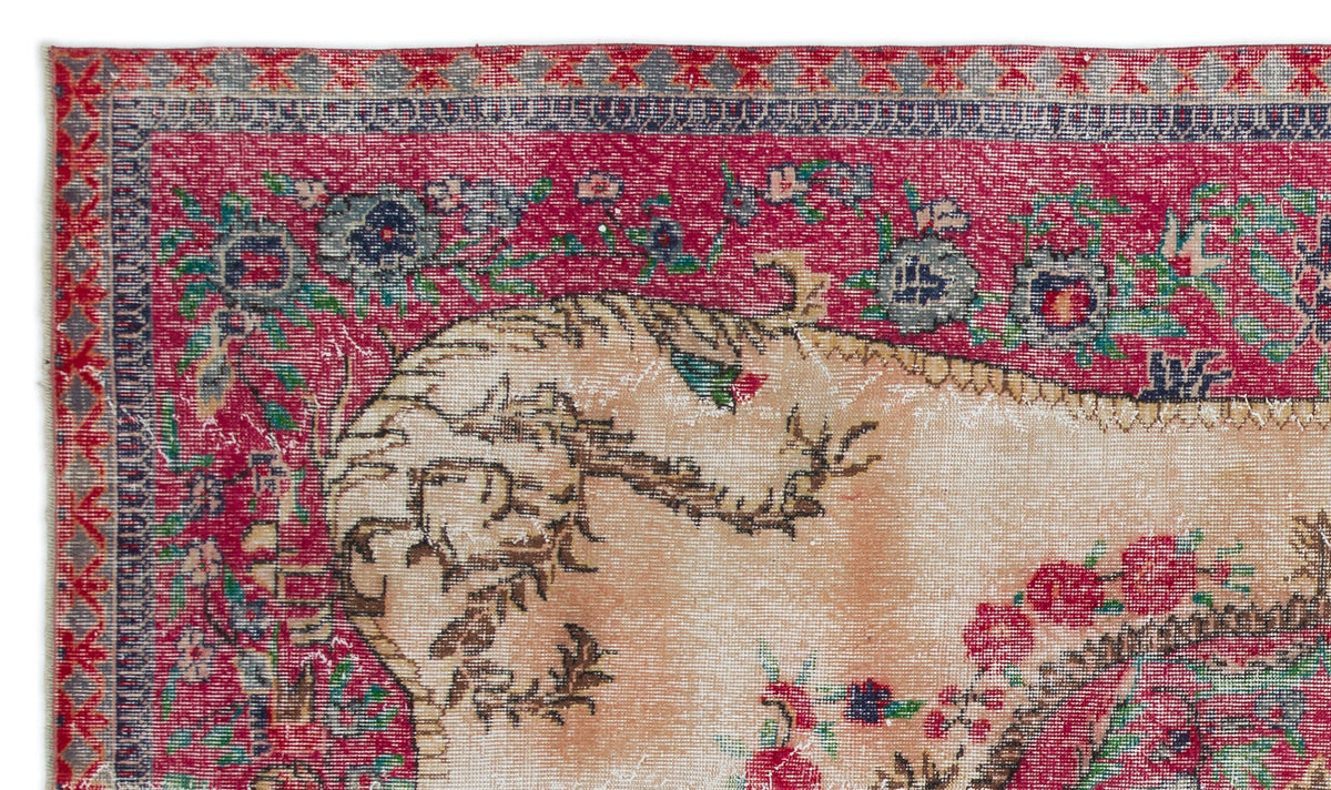 Distressed vintage-style rug with a deep red border, floral motifs, and a faded beige central field.