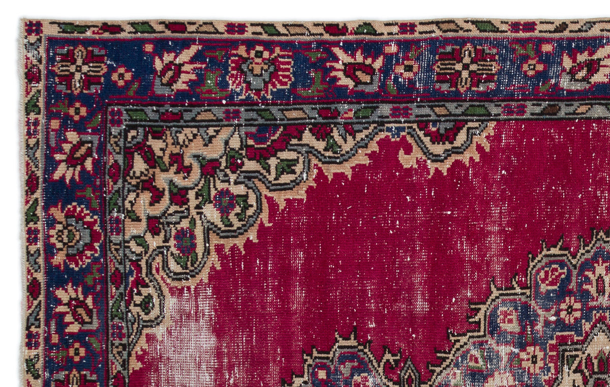 Distressed magenta rug with a navy blue floral border and intricate beige, green, and red traditional patterns.