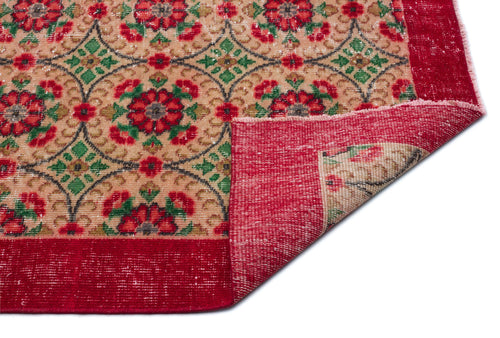 Load image 1 in gallery view. Beige rug with red and green floral medallion pattern and a wide red border, shown with a corner folded over.