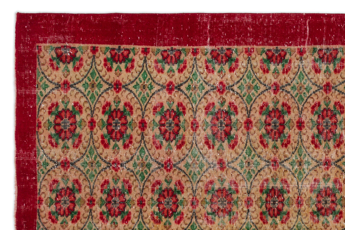 Tan rug with a red border and repeating floral medallion pattern in red, green, and black.