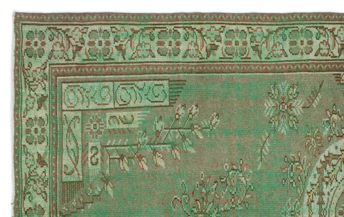 Load image 1 in gallery view. Sage green and brown vintage-style rug with a distressed floral border and geometric corner motifs.