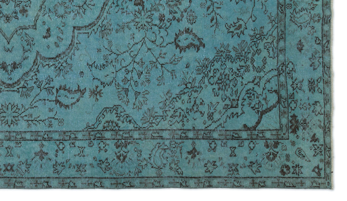 Teal rug with a distressed black floral pattern and a traditional border.