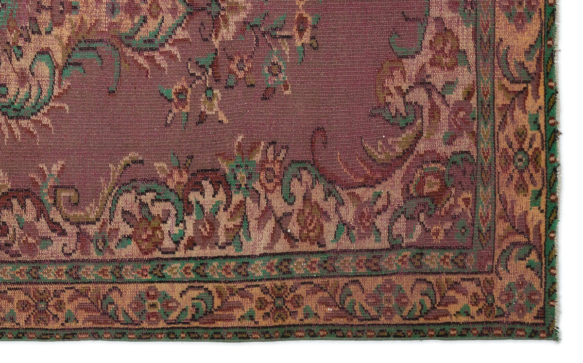 Plum-colored traditional rug with intricate floral motifs in green, tan, and brown, featuring a decorative border.