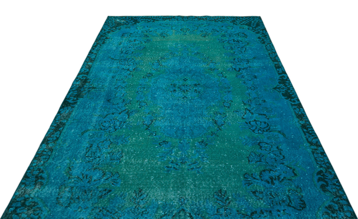 Teal and blue distressed vintage-style rug with a central floral medallion and ornate border.