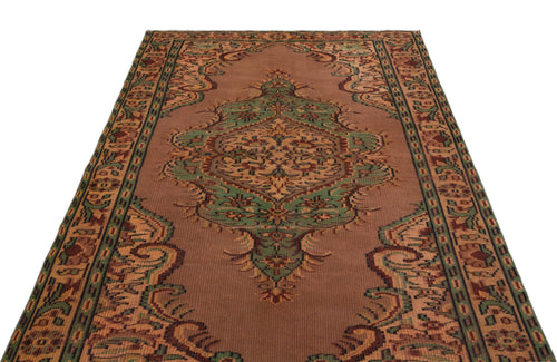 Load image 1 in gallery view. Brown traditional rug with a central green and tan floral medallion and a decorative geometric border.