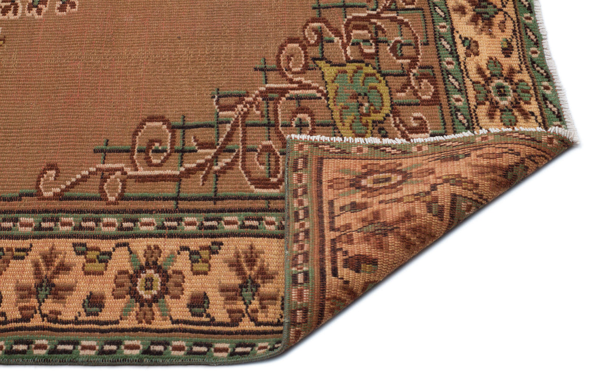 Brown and tan traditional rug with a floral border and geometric accents, shown with a corner folded over.