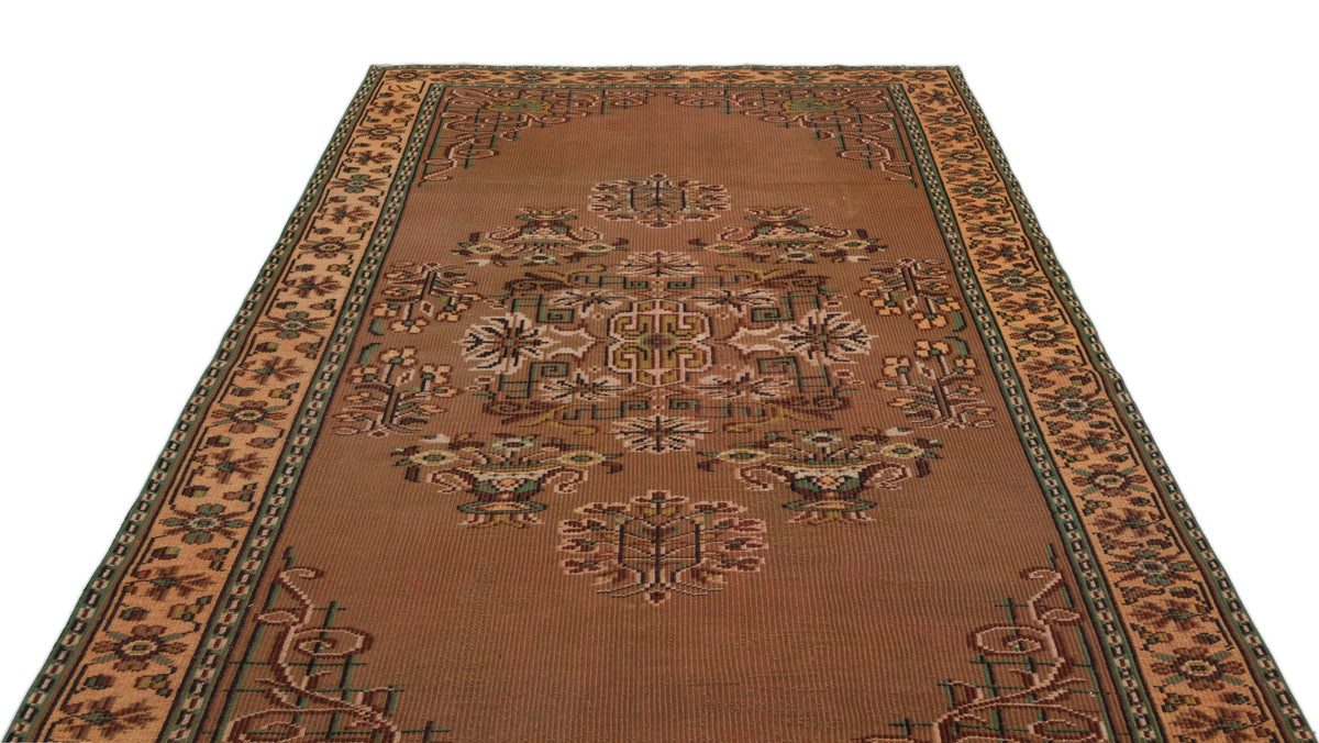 Brown traditional rug with a central geometric medallion and floral border in green, tan, and cream accents.