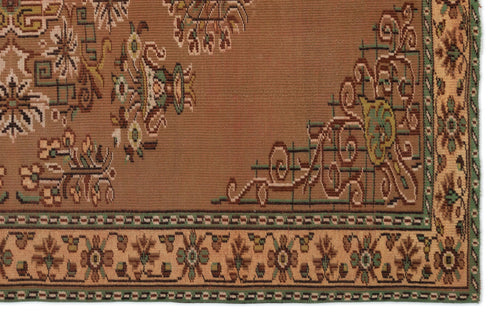 Load image 1 in gallery view. Brown rug with a traditional floral medallion pattern, geometric border, and accents in green, tan, and cream.