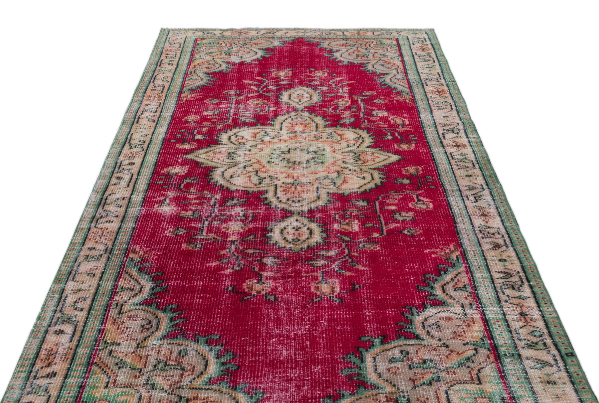 Distressed red vintage-style rug with a central floral medallion and green and beige border patterns.