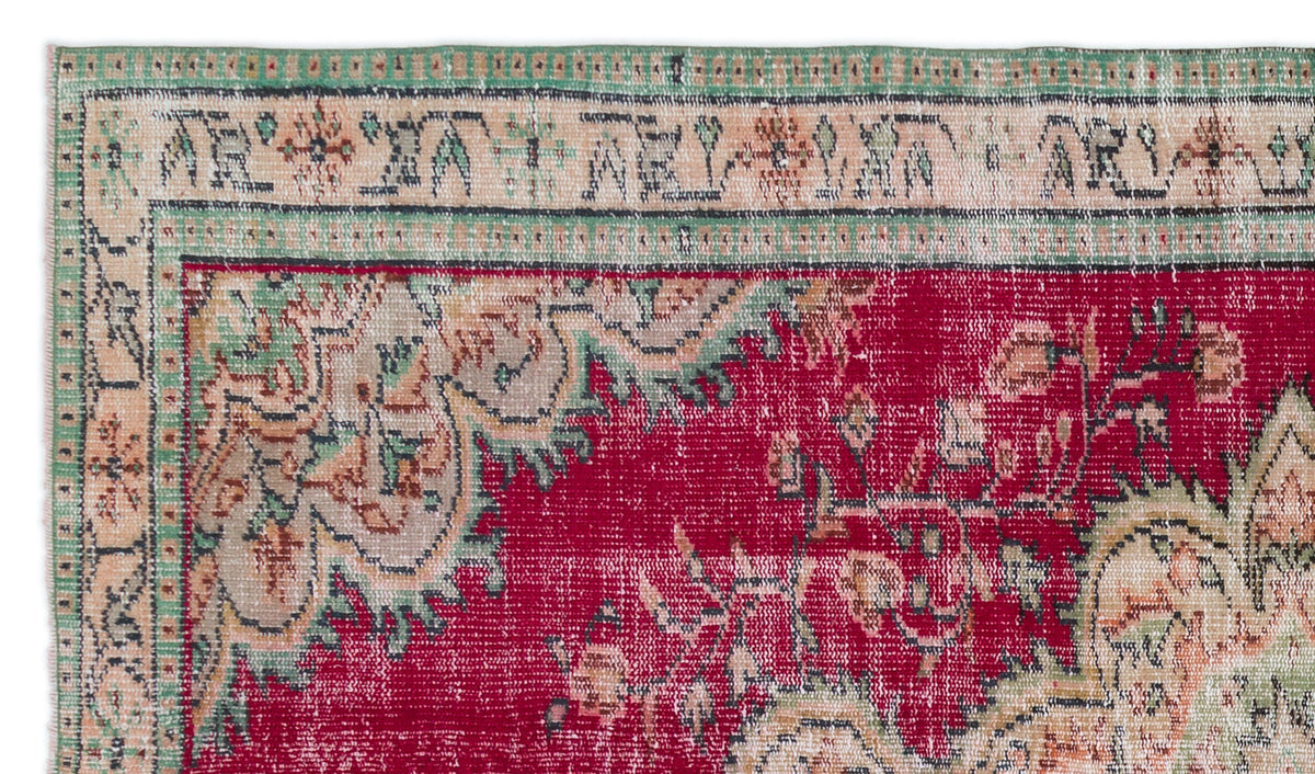 Distressed red vintage rug with a beige and green floral border and intricate traditional medallion pattern.