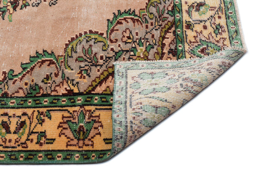 Load image 1 in gallery view. Peach, green, and yellow vintage-style rug with a floral medallion pattern and a folded corner showing the woven backing.