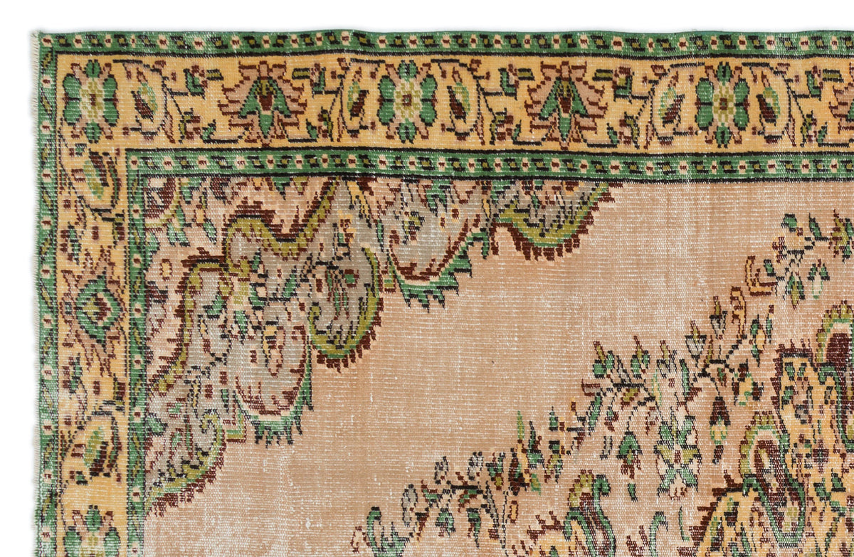 Peach, green, and brown traditional rug with a distressed floral medallion border and central pattern.
